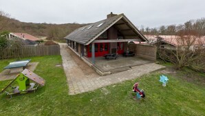A two-story house with a covered patio, a play area, and a small garden. - Unique Home at Bottom of Dunes near Center of Zoutelande (Zoutelande)