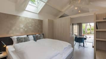 A bedroom with a large bed, a skylight, a desk with a chair, and a view of the outdoors.
