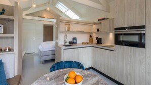 Une cuisine moderne dotée d’un îlot central, d’appareils électroménagers intégrés et d’un coin repas avec une table ronde et des chaises bleues.