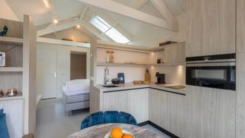 A modern kitchen with a central island, built-in appliances, and a dining area with a round table and blue chairs.