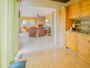 Een ruime woonkamer met een open haard, houten kasten en een eethoek.