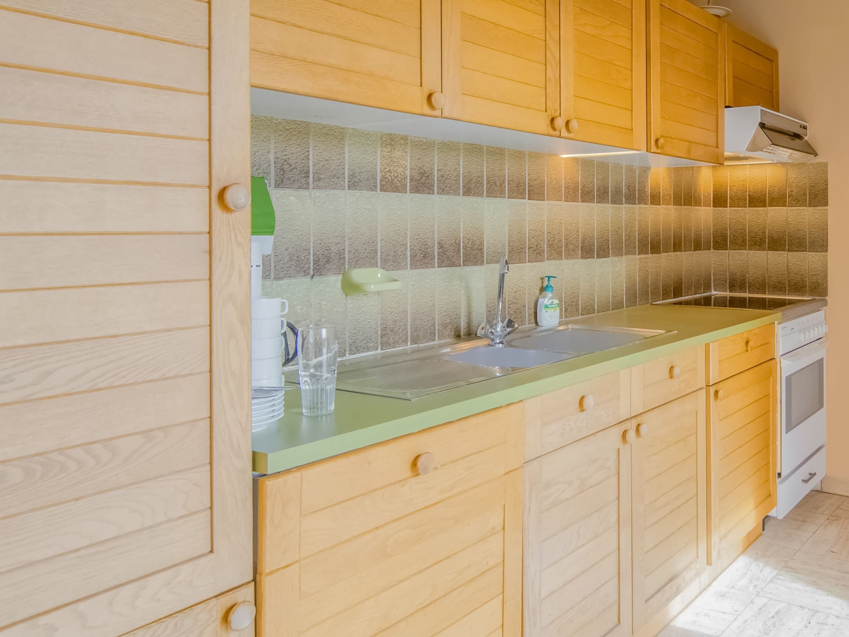A kitchen with wooden cabinets, a green countertop, a sink, and a built-in oven.