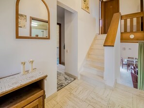 A staircase leading to a dining area, a mirror on the wall, and a wooden bench with a lace tablecloth.