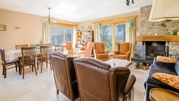 Ein Wohnzimmer mit Kamin, Essbereich und Blick ins Freie.