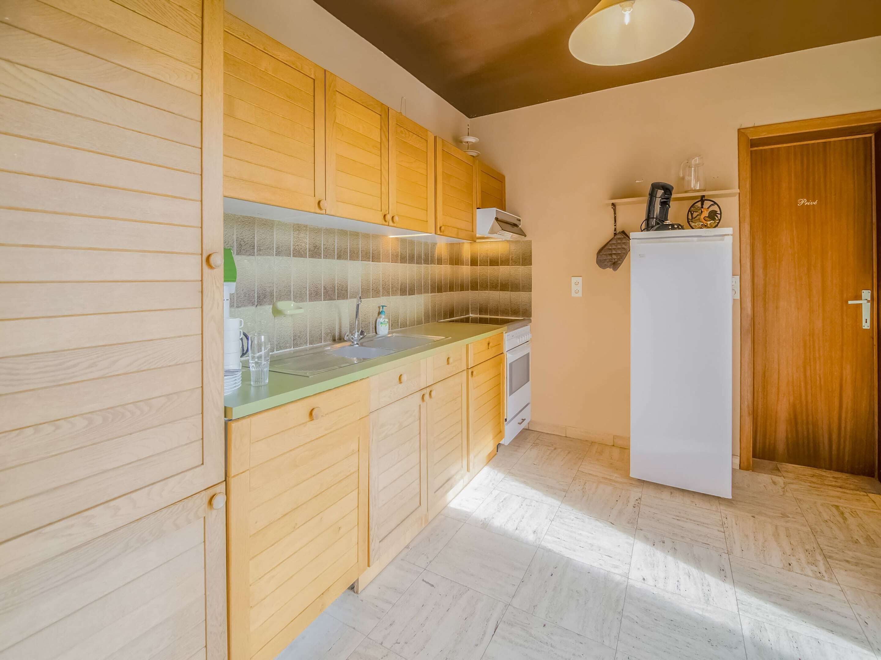 A kitchen with wooden cabinets, a sink, a stove, and a refrigerator.