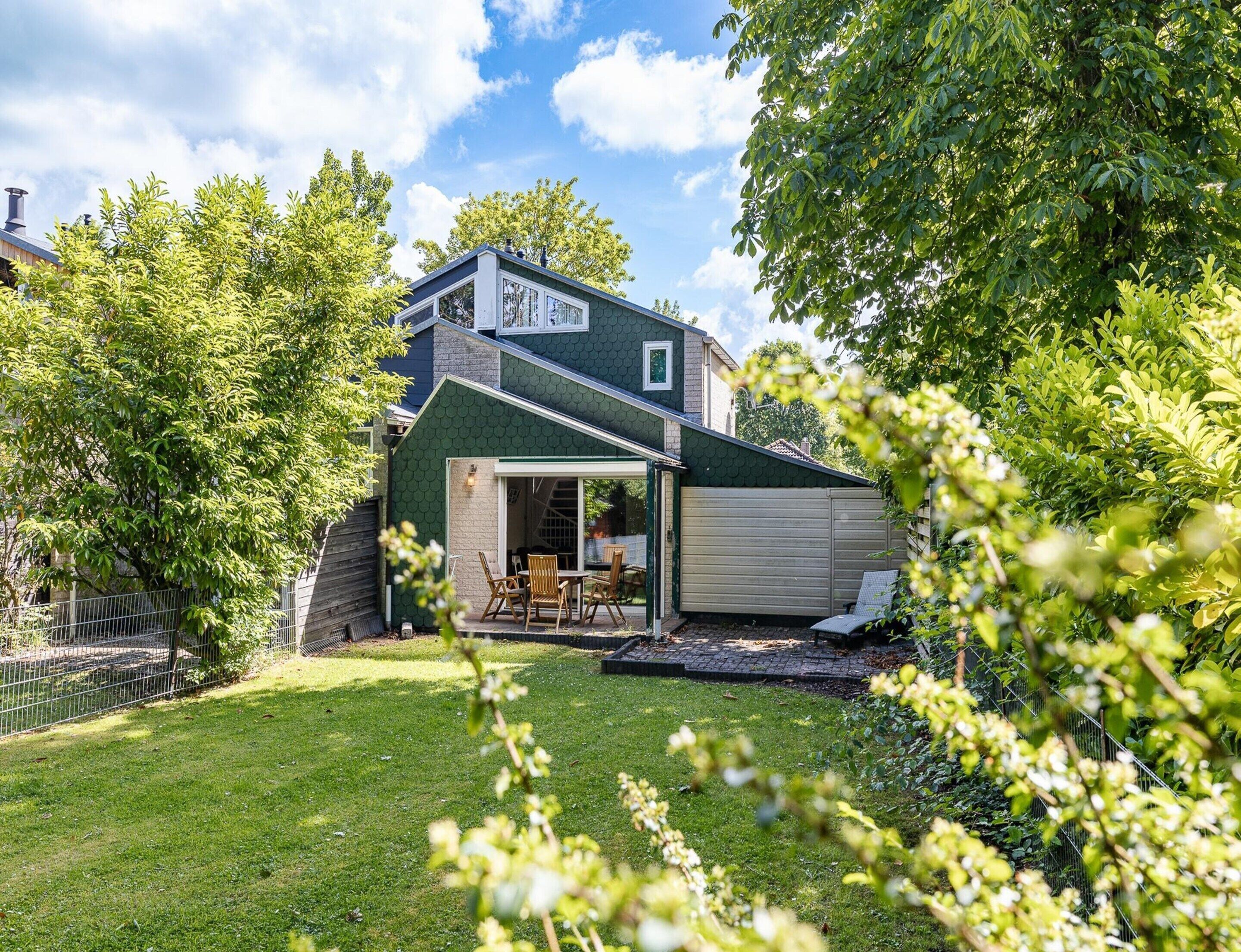 A house with a covered patio, a garage, and a well-maintained lawn.