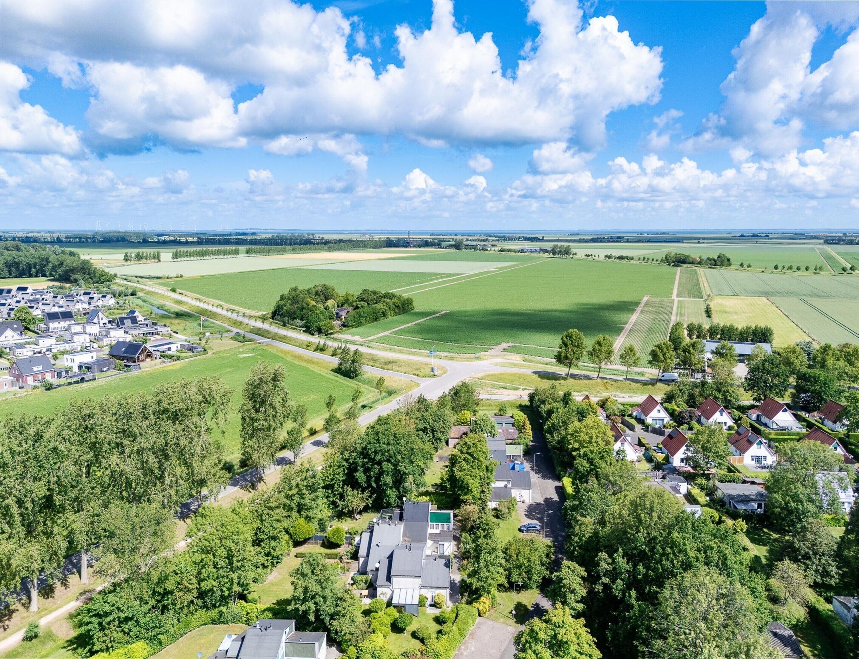 An aerial view of a residential area with houses, roads, and green fields.