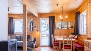 A cozy wooden cabin interior with a fireplace, a dining area, and a sofa. - Chalet in Dachstein West With Shared Pool (Annaberg-Lungoetz)