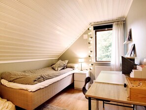 A small, cozy bedroom with a sloped ceiling, a bed, a desk, and a window with curtains. - 6 Person Holiday Home in Torsby (Torsby)