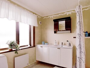 A bathroom with a window, a sink, a mirror, and a radiator. - 6 Person Holiday Home in Torsby (Torsby)