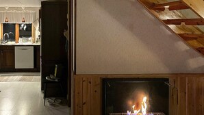 A cozy kitchen with a fireplace, wooden cabinets, and a dining area. - 6 Person Holiday Home in Torsby (Torsby)