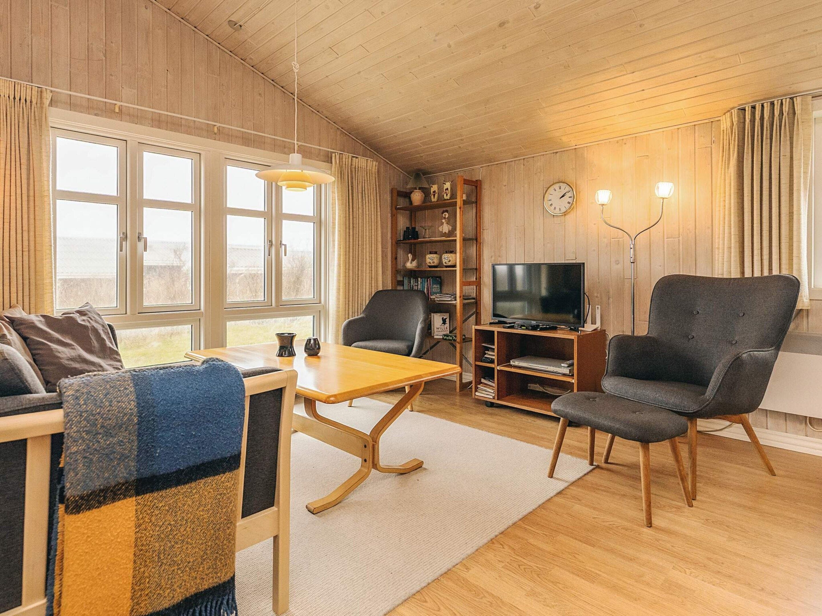 A cozy living room with a sofa, armchair, wooden coffee table, and a television on a stand.