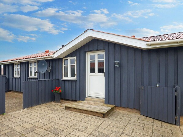 A building with a dark exterior, a white door, and a tiled roof. - 6 Person Holiday Home in Lokken (Lokken)