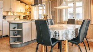 A modern kitchen with wooden cabinets, a microwave, and a sink. There is a dining area with a table and chairs. - 6 Person Holiday Home in Lokken (Lokken)