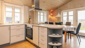 A modern kitchen with a central island, wooden cabinets, and a built-in oven.