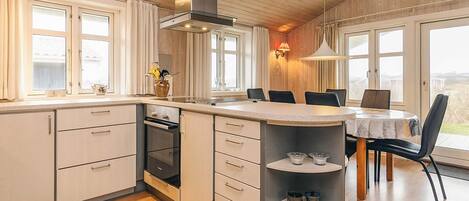 A modern kitchen with a central island, wooden cabinets, and a built-in oven.