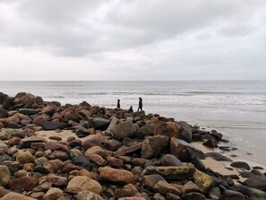 A rocky beach with large boulders and a calm sea. - 6 Person Holiday Home in Lokken (Lokken)