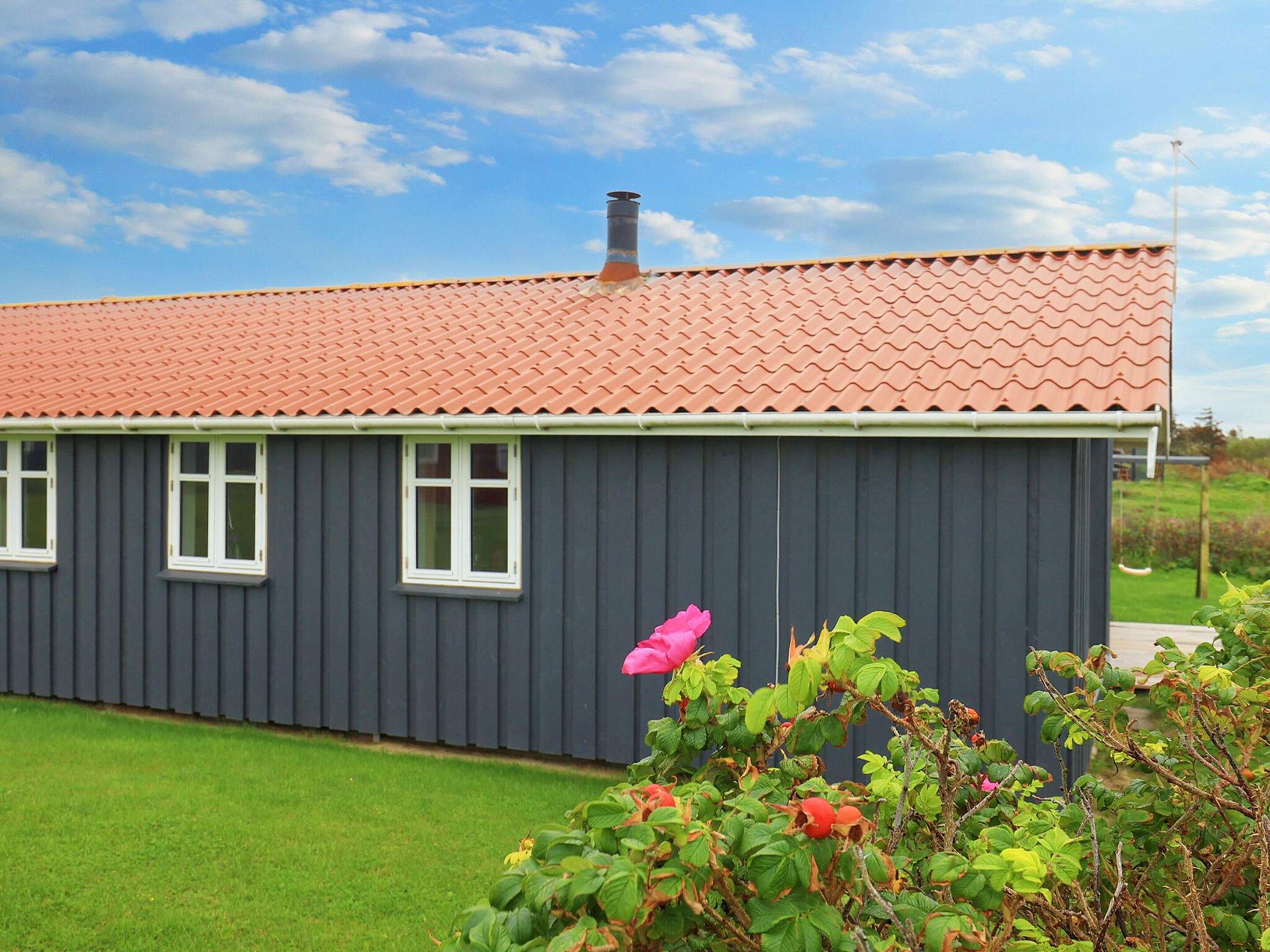 A single-story building with a red-tiled roof and a grey exterior wall.