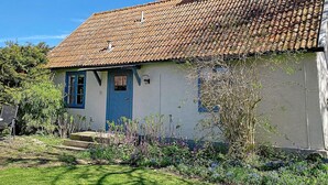A house with a tiled roof, a blue door, and a small garden with flowers. - 6 Person Holiday Home in Lottorp (Löttorp)