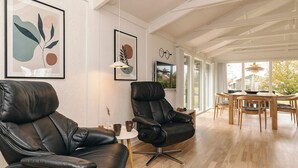 A modern living room with leather chairs, a dining table, and artwork on the walls.