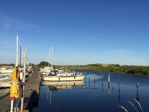 A calm marina with boats docked, a clear sky, and a calm water surface reflecting the boats.