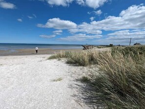 A beach with sand, grass, and a person walking. - 4 Star Holiday Home in Hals (Hals)