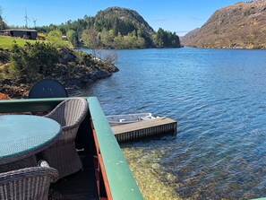 A lakeside deck with wicker furniture and a floating dock. - 8 Person Holiday Home in Egersund, Norge (Egersund)