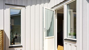 En moderne facade med træterrasse, skydedør og et vindue.