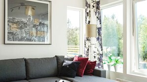 En moderne stue med en grå sofa, et glasbord og et indrammet bybillede.