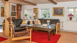 Ein gemütliches Wohnzimmer mit Holzboden, einem roten Teppich, einem Couchtisch aus Holz und einem Sofa.