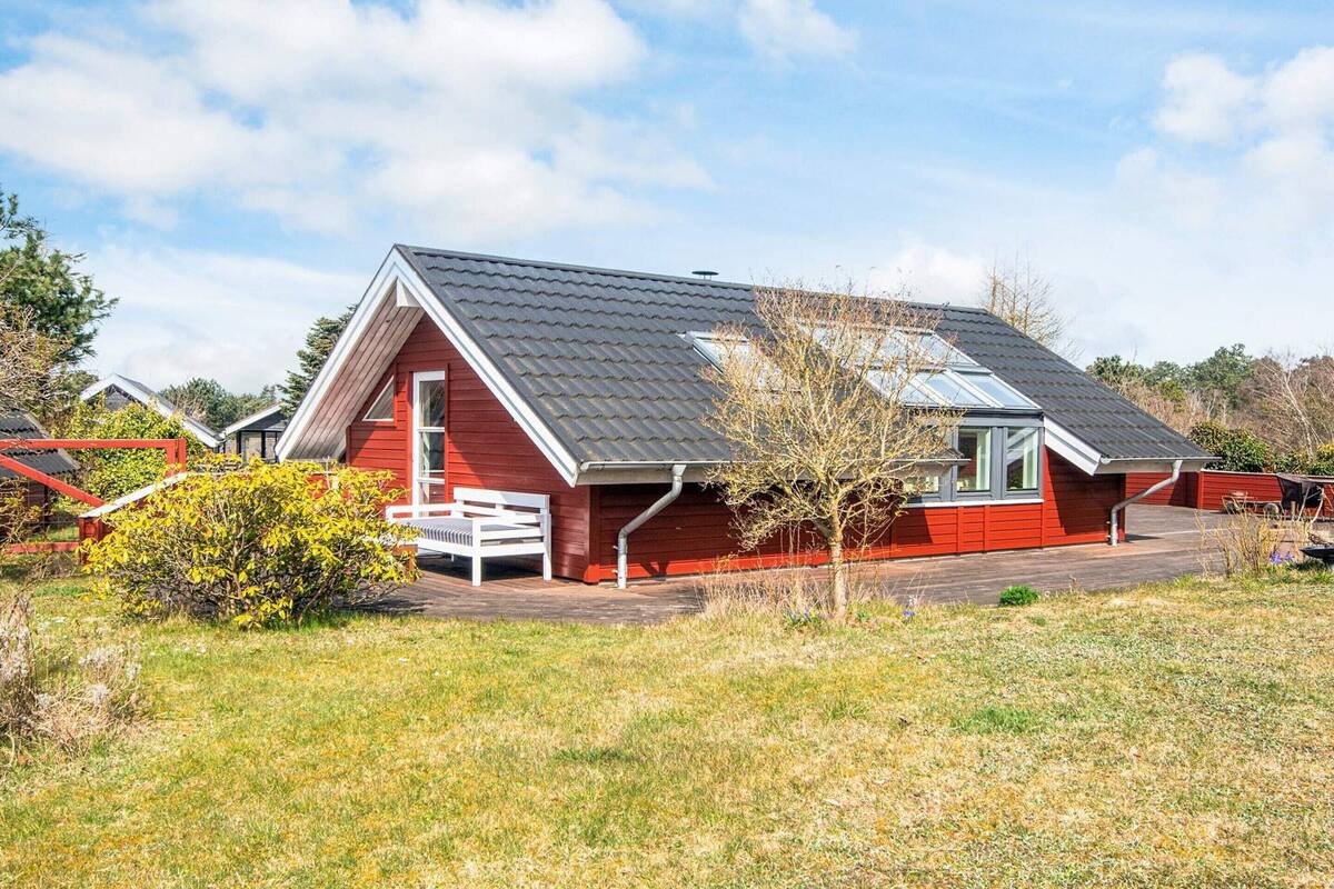 Et rødt hus med skråt tag og en lille veranda.