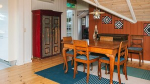 A dining area with a wooden table and chairs, a chandelier, and a red cabinet. - 7 Person Holiday Home in Ebeltoft (Ebeltoft)