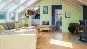 A spacious attic room with high ceilings, skylights, a cozy seating area with a sofa and armchairs, a fireplace, and a bed with a view. - 7 Person Holiday Home in Ebeltoft (Ebeltoft)