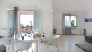A modern living room with a dining area, large windows, and a view of the outdoors. - Grand Villa in Tavullia (Tavullia)
