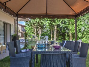 An outdoor patio with a glass table and wicker chairs, surrounded by a canopy. - Grand Villa in Tavullia (Tavullia)