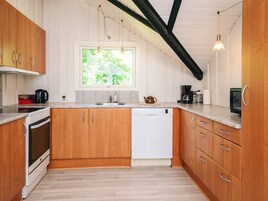 Una cocina con muebles de madera, lavavajillas, estufa y ventana con vistas a zonas verdes.