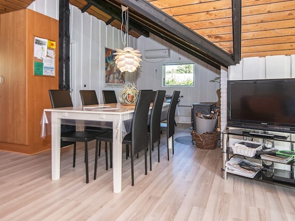 A modern dining area with a wooden table, black chairs, and a hanging light fixture. - 6 Person Holiday Home in Ansager (Ansager)