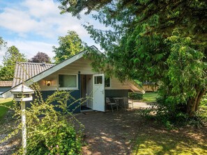 A small, single-story house with a sloped roof, a front door, and a small patio area with a table and chairs. - 6 Person Holiday Home in Ansager (Ansager)