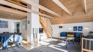 A spacious living area with a high ceiling, wooden beams, a staircase, a dining table, and a sofa. - 10 Person Holiday Home in Norre Nebel (Norre Nebel)