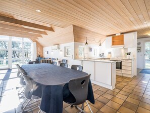 A modern kitchen with a large island, white cabinetry, and a dining area with a table and chairs.