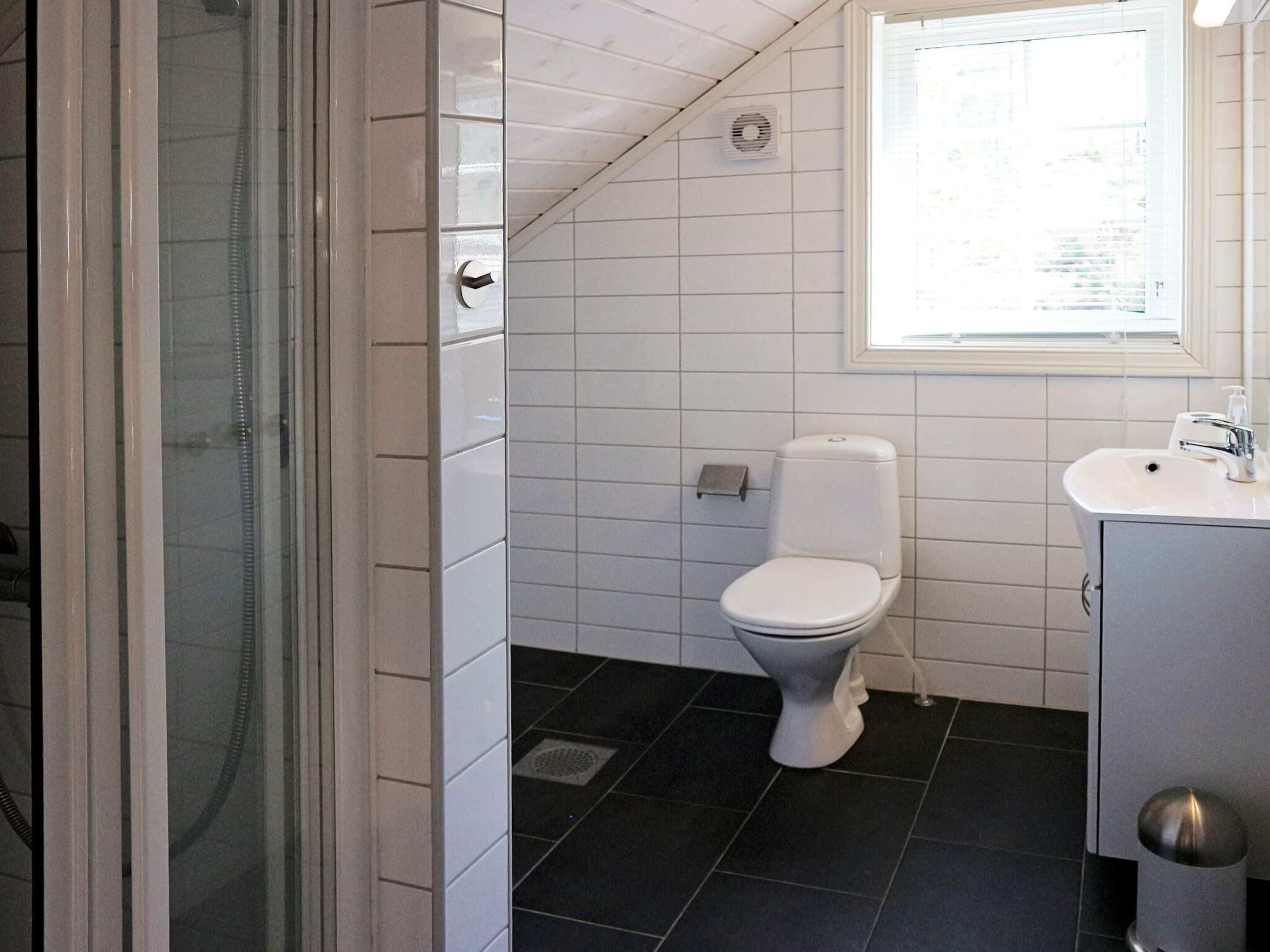 A bathroom with a toilet, sink, and shower area.