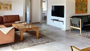 Una sala de estar con techo de madera, televisor en la pared, sofá, mesa de centro y alfombra.