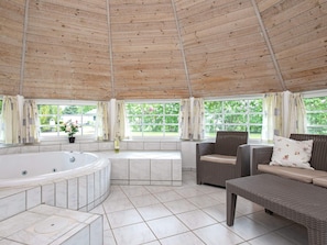 A spa area with a hot tub, wicker furniture, and large windows. - Holiday Home in VÃ¦ggerlÃ¸se (Vaeggerlose)
