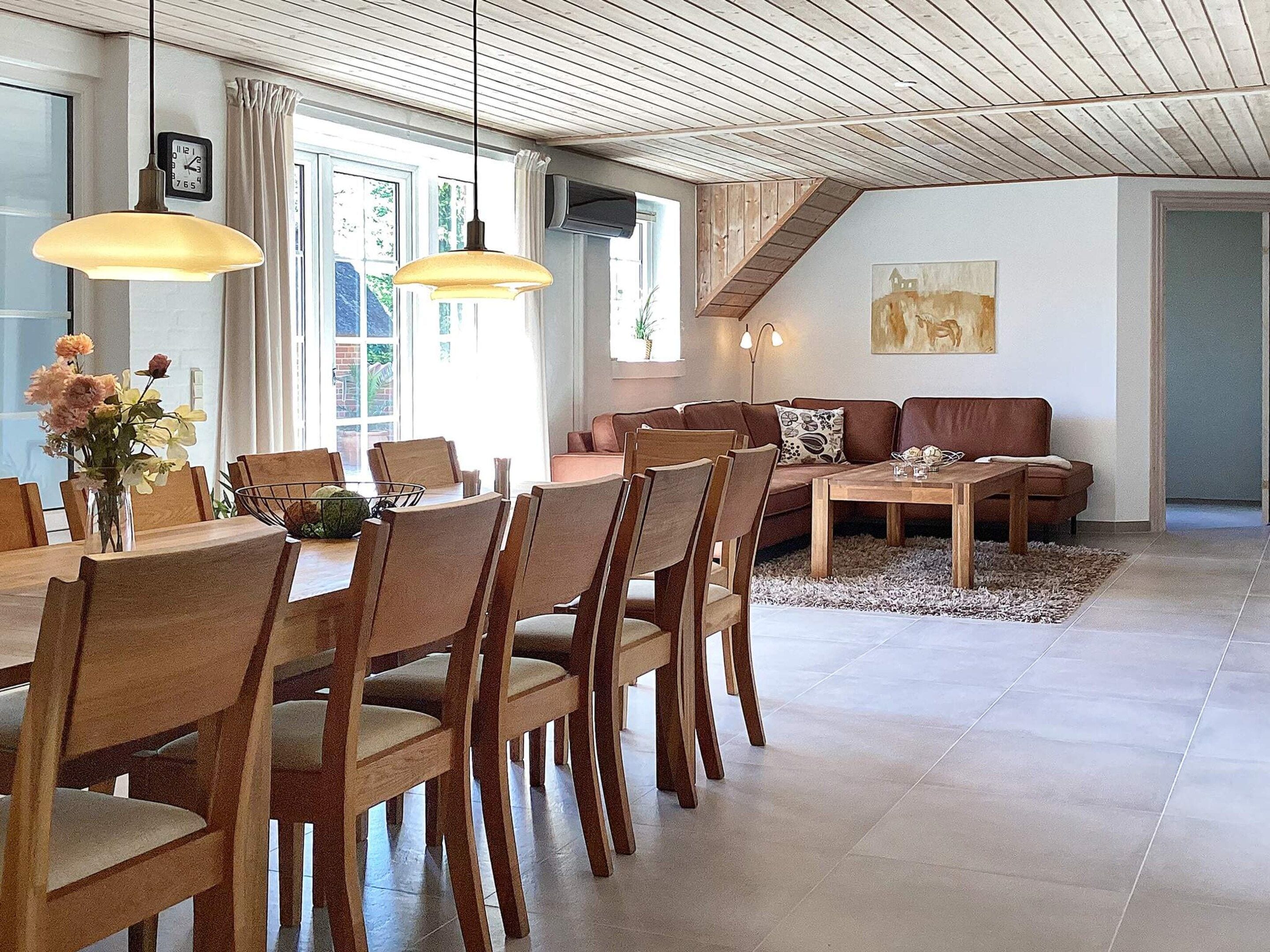 A modern living room with a dining area, wooden furniture, and a staircase.