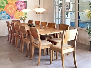 A dining area with a wooden table and chairs, a vase with flowers, and a colorful floral painting on the wall. - Holiday Home in VÃ¦ggerlÃ¸se (Vaeggerlose)