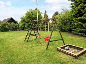 A wooden swing set in a grassy yard with a sandbox nearby. - Holiday Home in VÃ¦ggerlÃ¸se (Vaeggerlose)