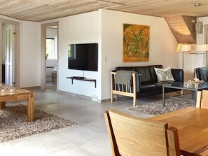 Ein modernes Wohnzimmer mit einem Flachbildfernseher, einem Sofa, einem Couchtisch und einem Gemälde an der Wand.