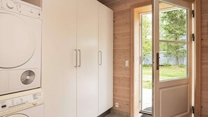 A laundry room with a washing machine, dryer, and wooden cabinets. - Holiday Home in LÃ¦sÃ¸ (Læsø)