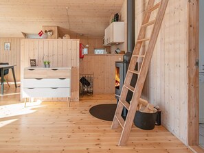 A wooden interior with a fireplace, a ladder, and a dining area.