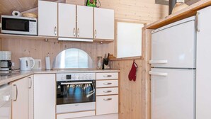Kompakti keittiö, jossa on valkoiset kaapit, Bosch-uuni, mikroaaltouuni ja jääkaappi.